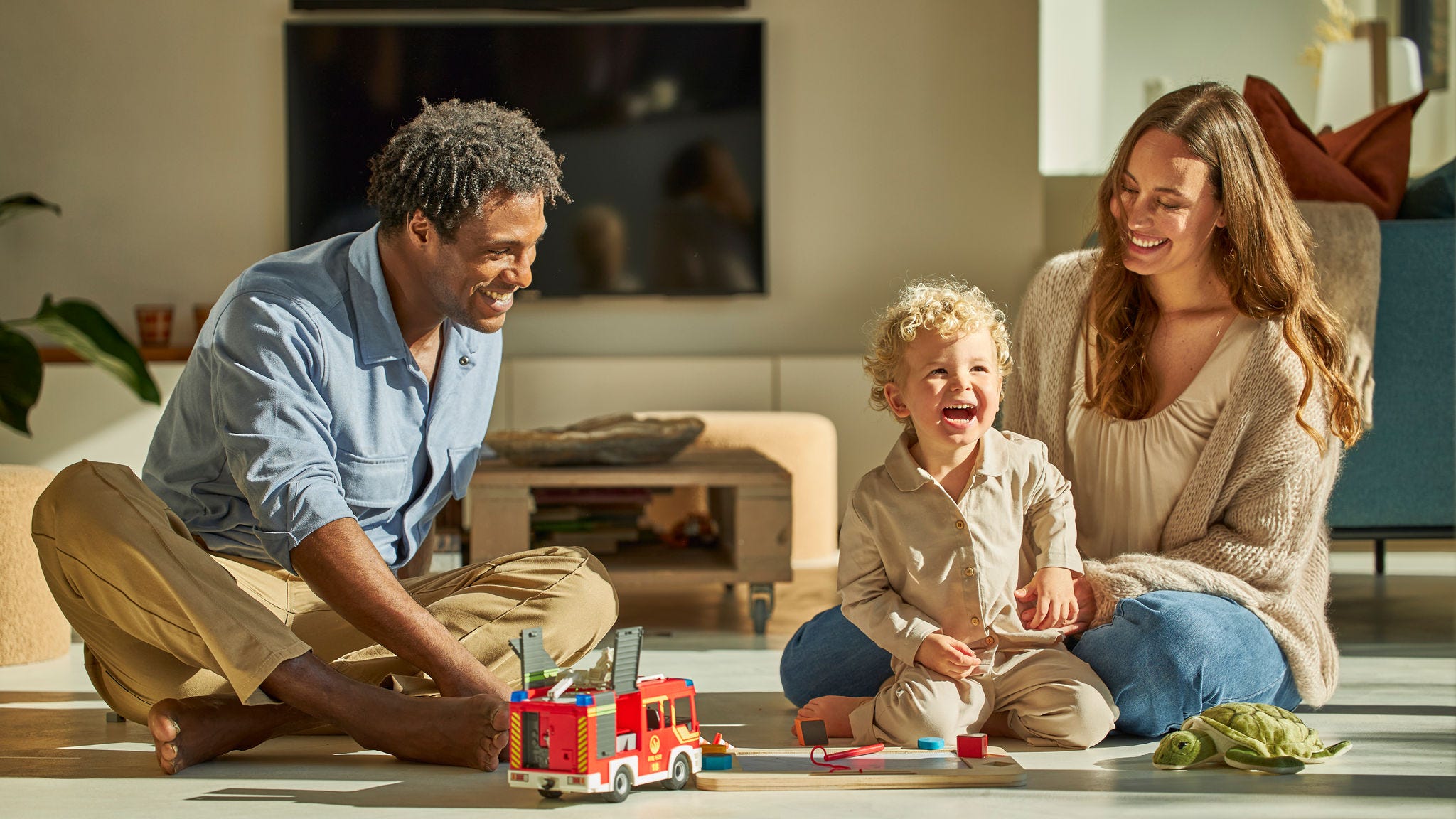 Parents and toddler sitting on the floor playing with toys enjoying a ventilated home