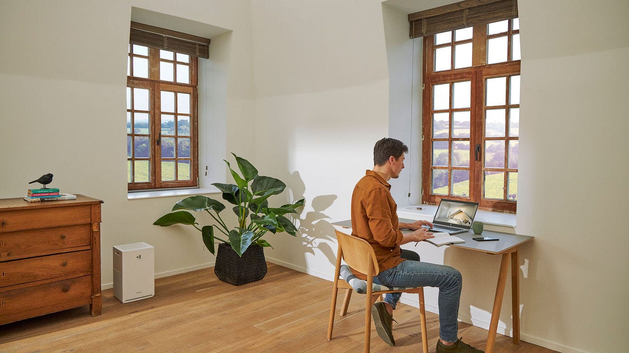 Hombre trabajando en un escritorio desde la sala de su casa