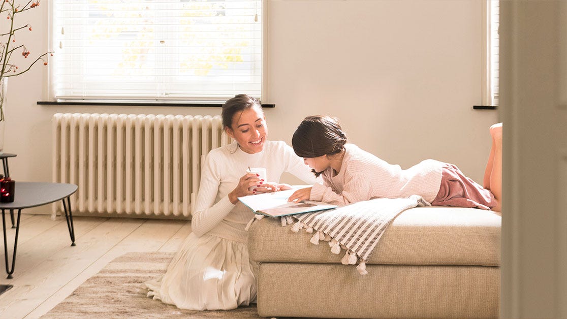 Madre e hija leyendo un libro mientras disfrutan de la aerotermina de Daikin