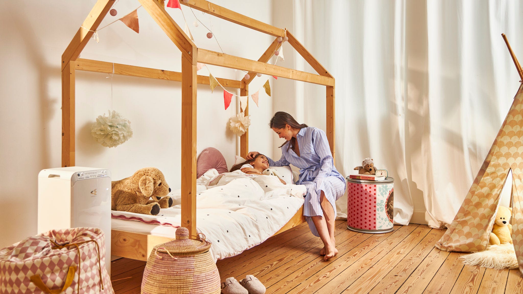 Madre acostando a su hijo en su hogar saludable gracias al purificador de aire Daikin en la habitación de los niños