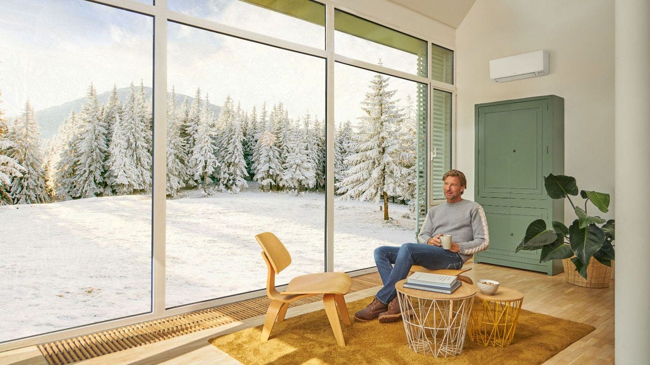 Hombre sentado en el sofá y disfrutando de la calefacción con aire acondicionado