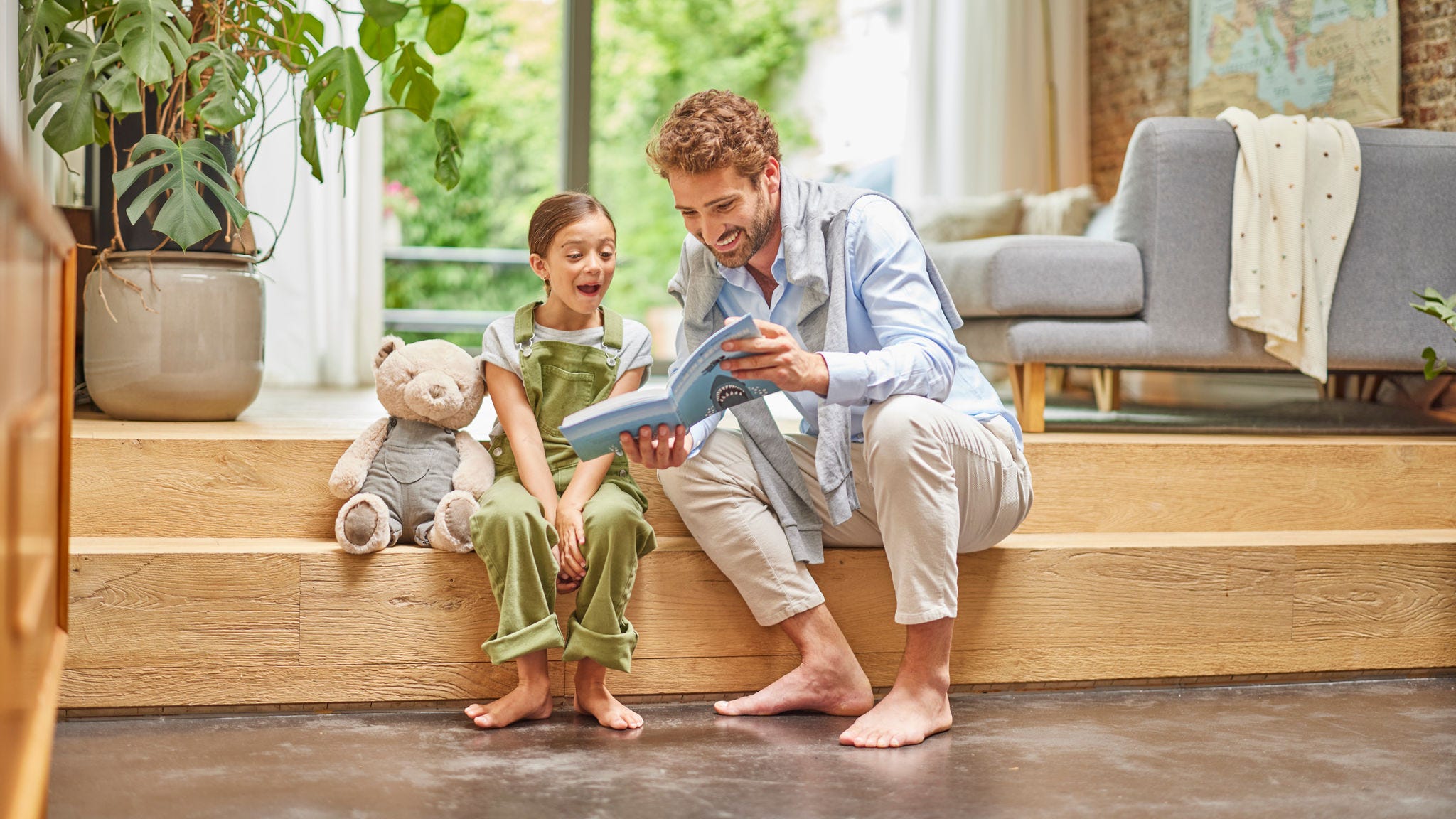 Padre e hija leen un libro sobre el suelo radiante de su hogar