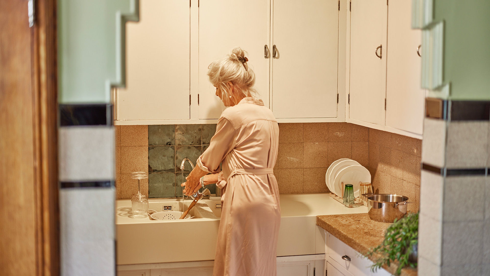 Mujer de espaldas lavándose las manos en la pica de su cocina