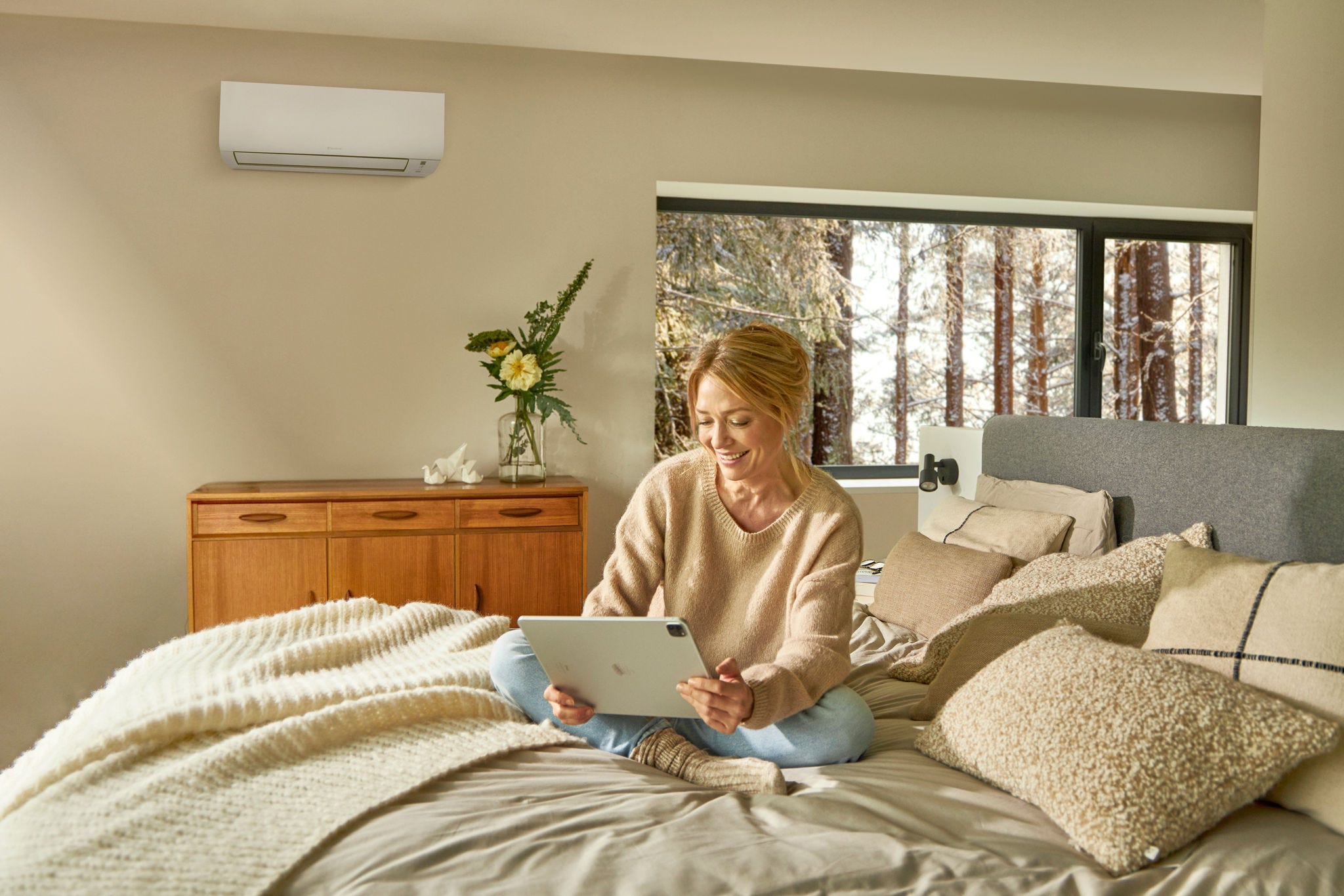 Mujer en su cama disfrutando de la calefacción de su aire acondicionado Daikin