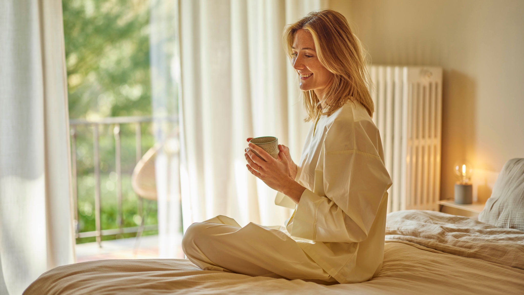Mujer toma una taza de té en su piso al calor de sus radiadores por aerotermia