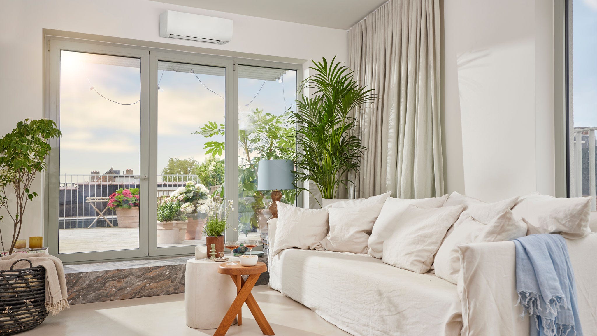 Una estancia luminosa y espaciosa con un discreto equipo de aerotermia tipo Split blanco montado en la pared que proporciona calefacción y aire acondicionado