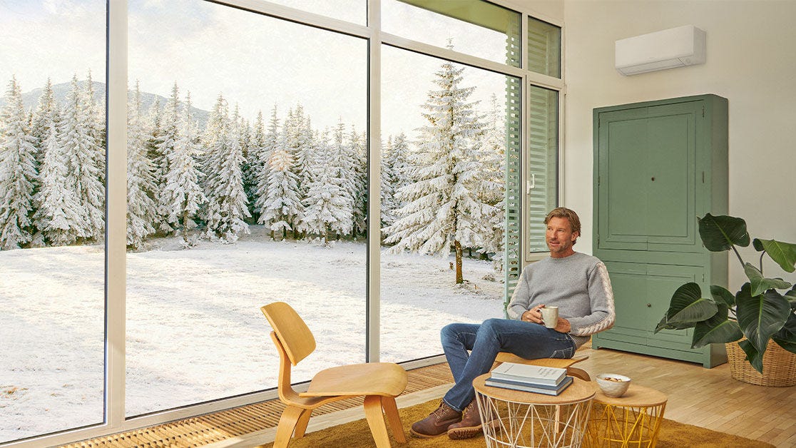 Hombre sentado en el salón con una taza en la mano y disfrutando de la aerotermia de Daikin