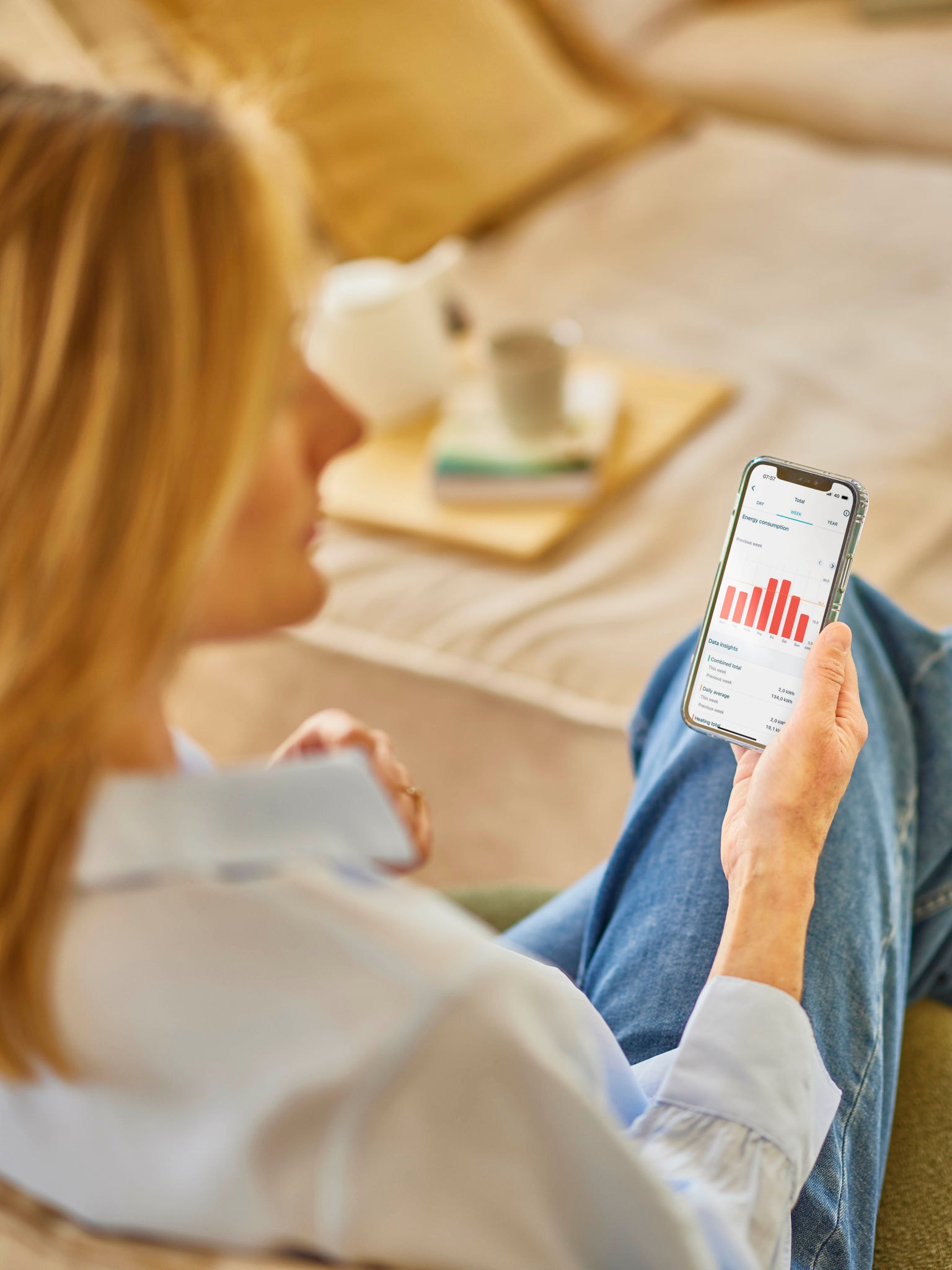 Una mujer rubia mirando su consumo energético en una aplicación de su teléfono