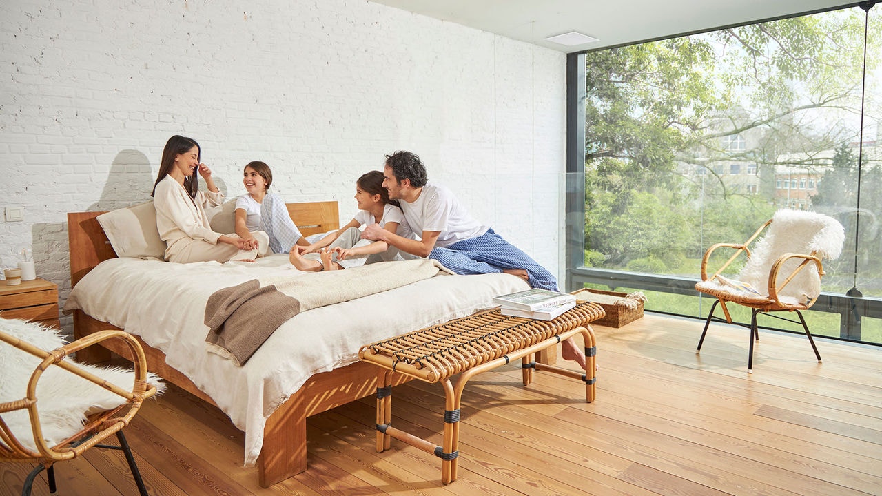 Familia de padres e hijos sonriendo en la cama de su hogar