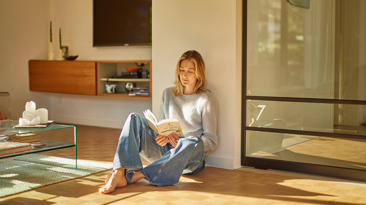 Mujer disfrutando de la climatización Daikin mientras se lee u libro en el salón