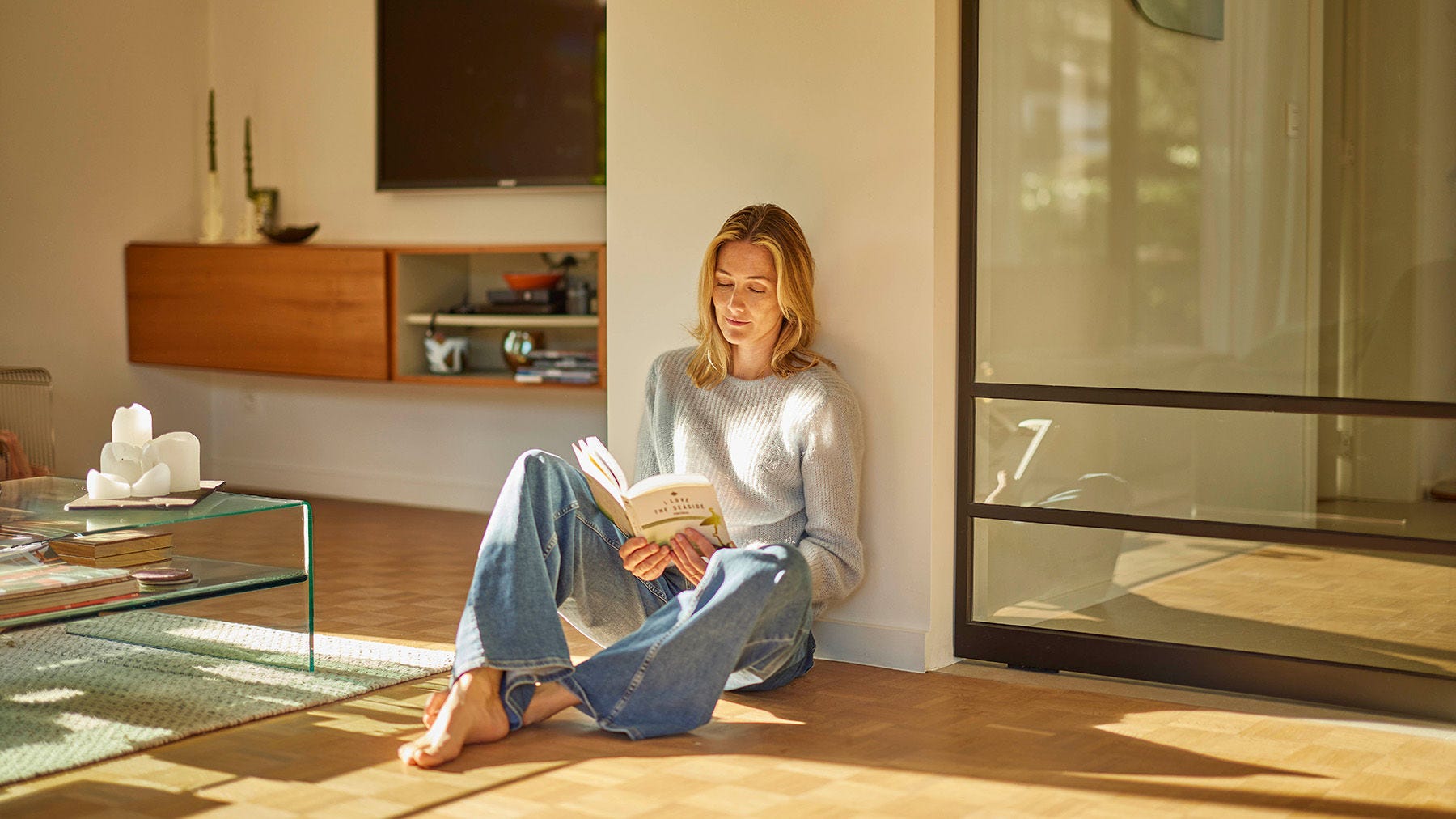 Mujer sentada en el suelo del salón leyendo un libro 