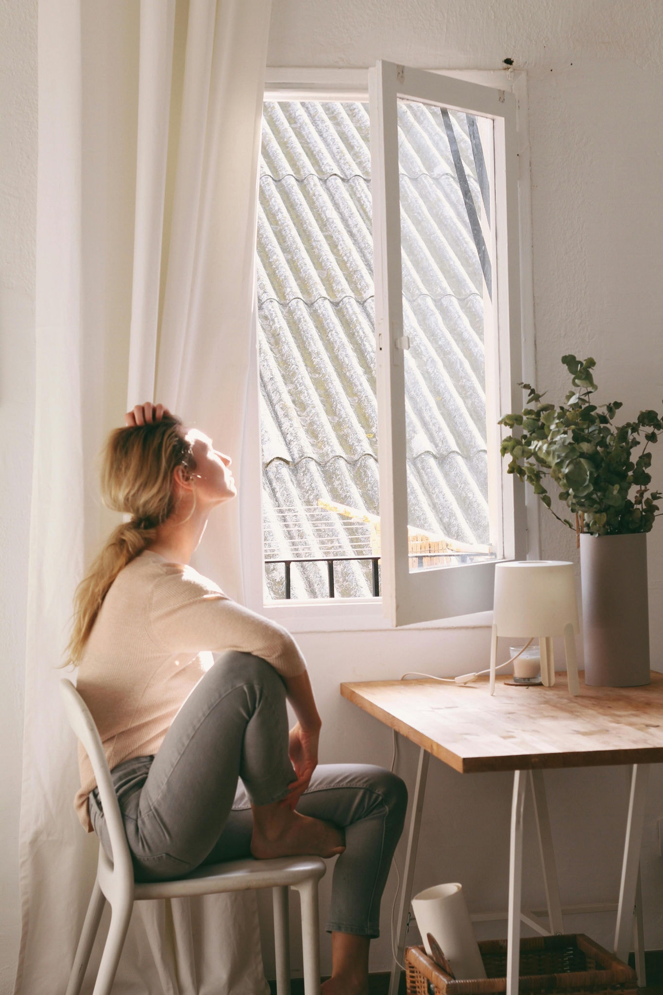 Mujer mira por la ventana mientras disfruta de su purificador de aire para casa
