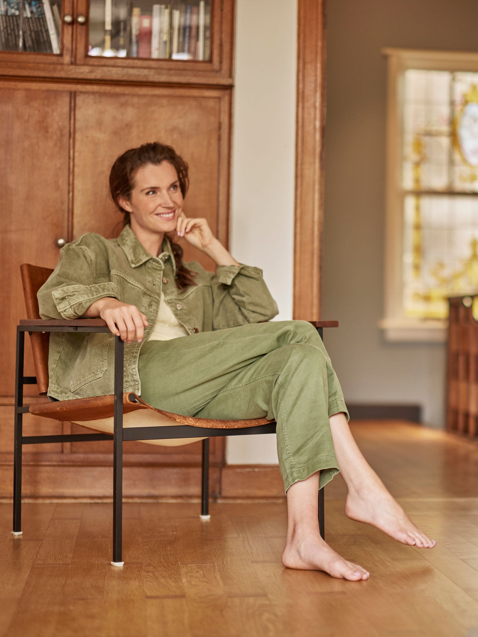 Mujer sentada en su sillón, descalza, sonriendo y mirando al frente