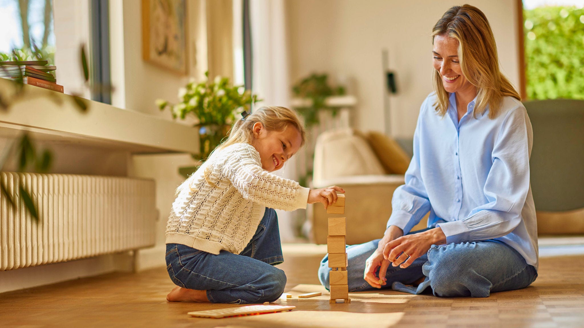 Niña y su madre jugando en su casa con radiadores por aerotermia