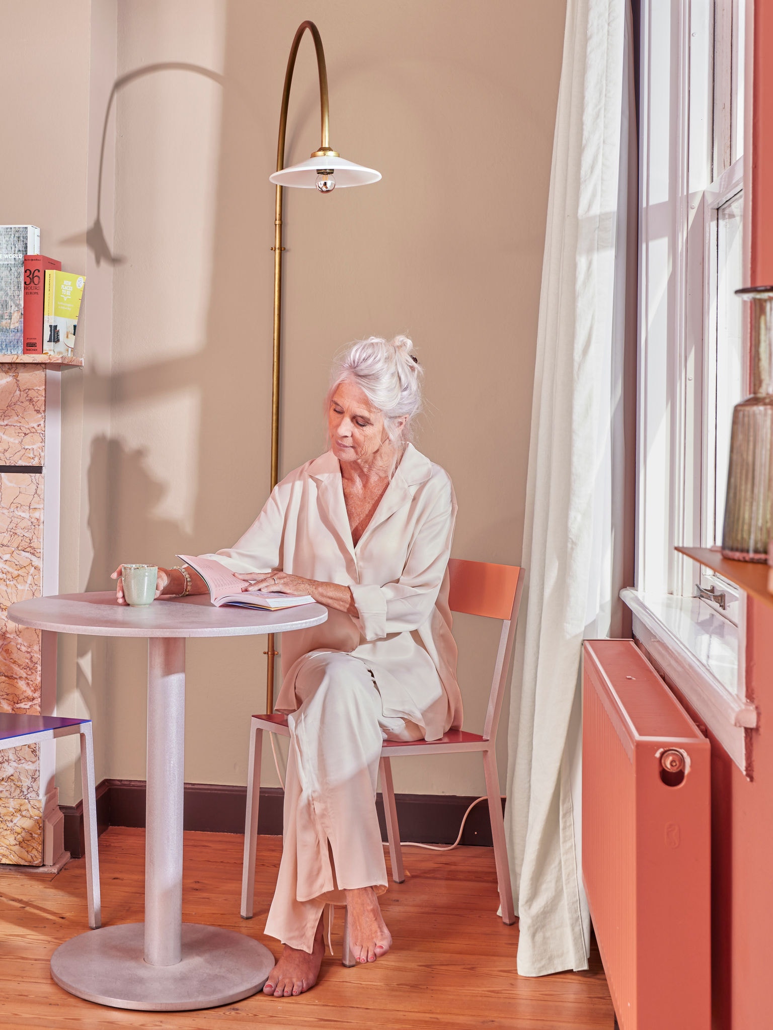Mujer leyendo en una mesa junto al radiador utilizando un sistema de calefacción doméstico con equipo de aerotermia