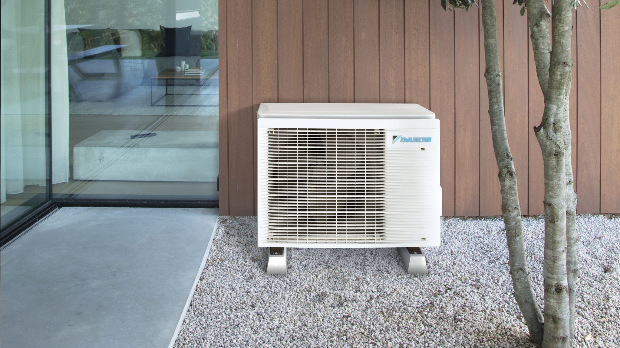 Equipo de aerotermia con fuente de aire compacto instalado discretamente en el exterior, junto a una casa moderna
