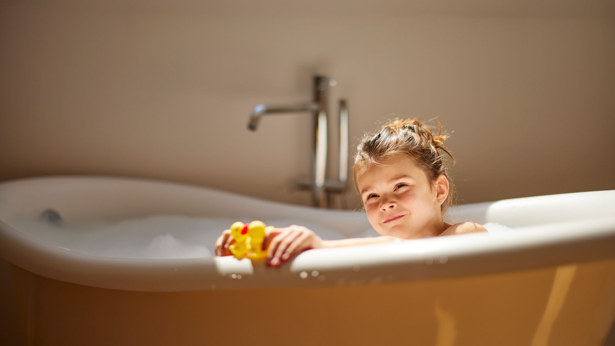 Niña disfrutando de un baño caliente, gracias al funcionamiento de la aerotermia para producir agua caliente sanitaria