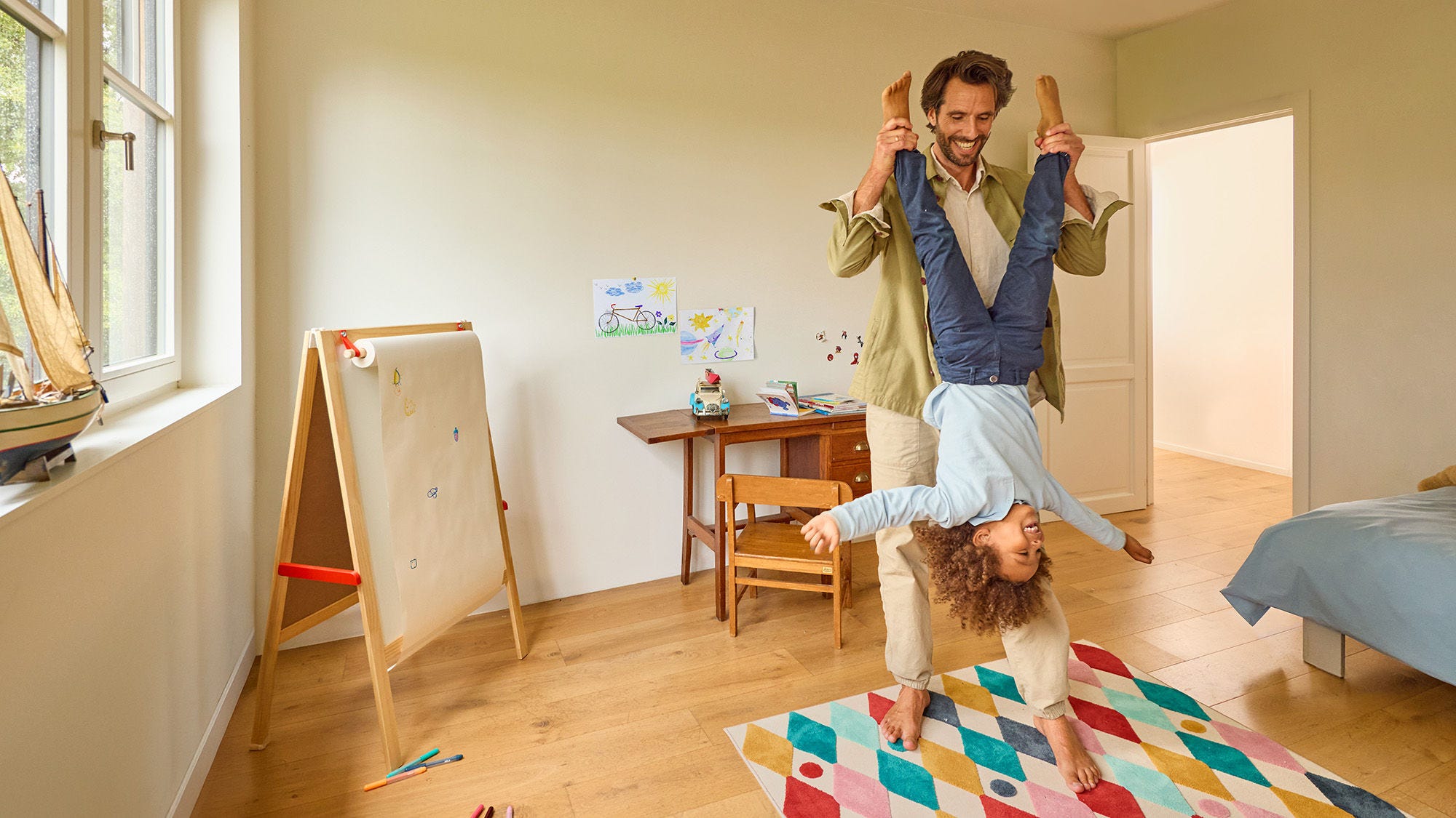 Hombre cogiendo volteando a su hijo de cabeza, cogiéndolo por los pies