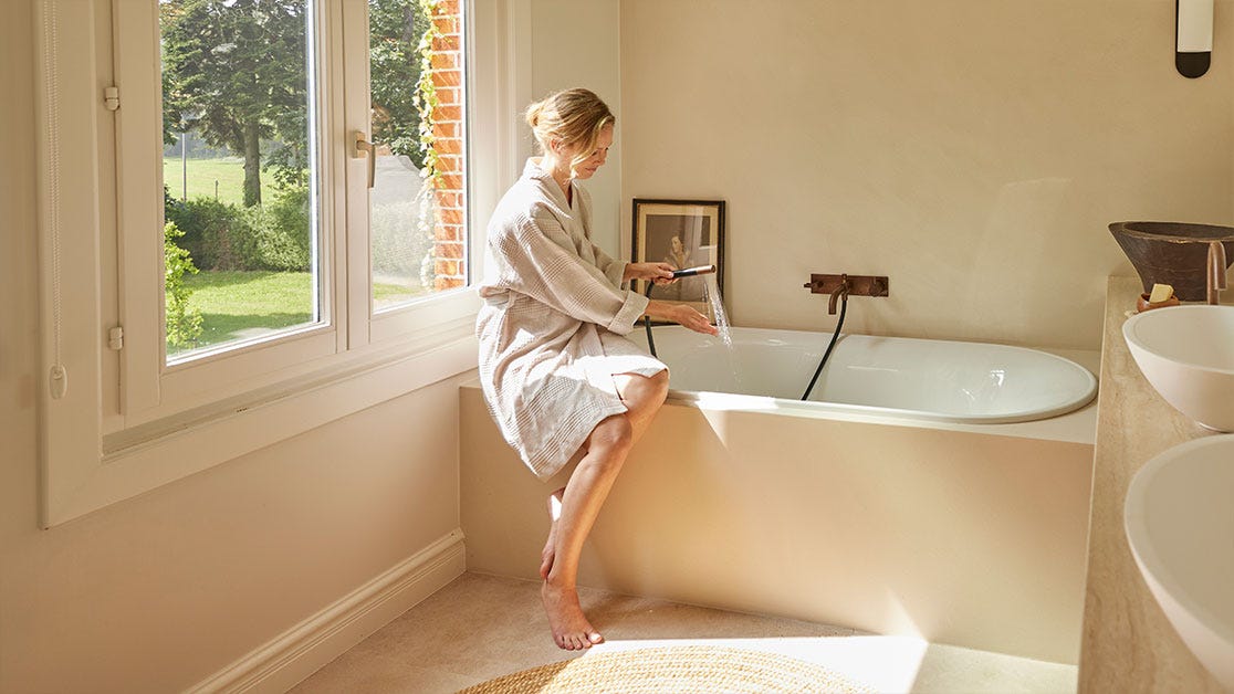 Mujer sentada en el baño sujetando la ducha encendida