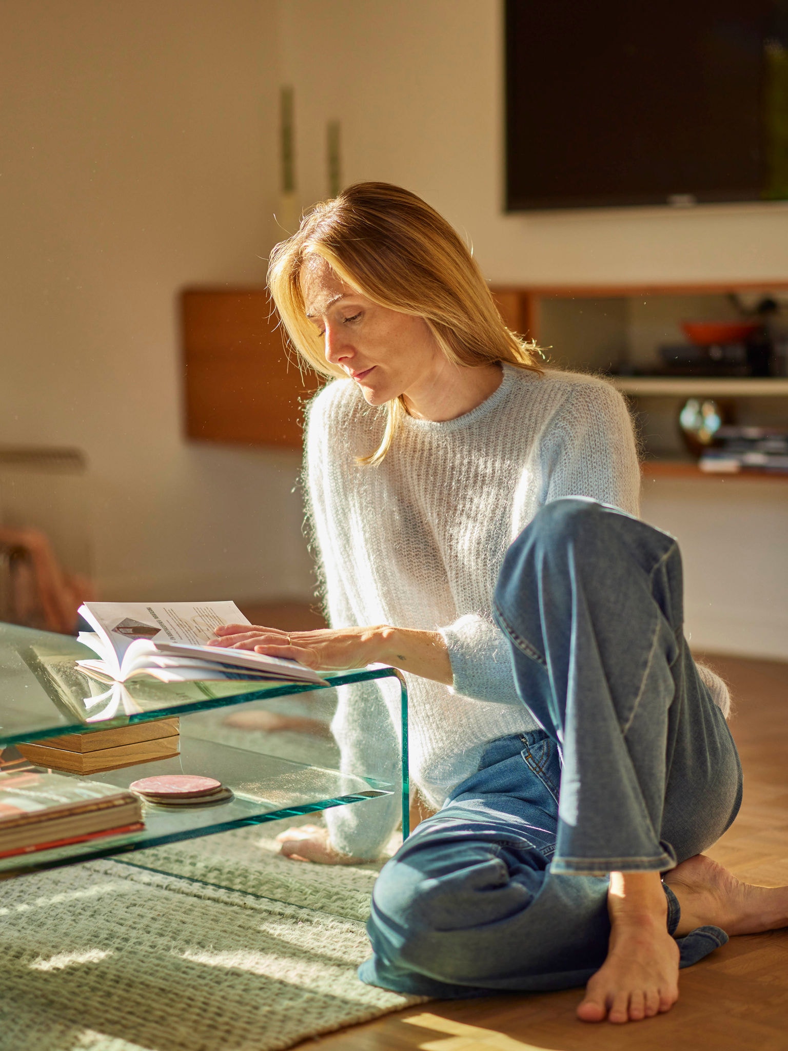 Mujer relajándose con un libro en una casa energéticamente eficiente que se calienta con un equipo de aerotermia