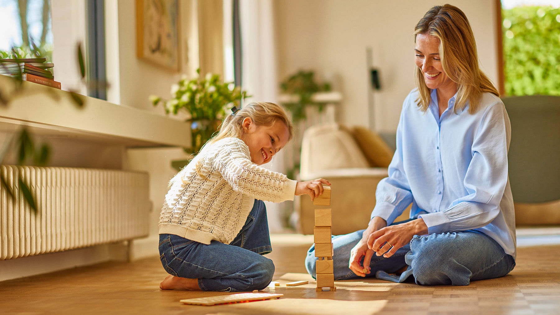 Madre e hija jugando en el suelo del salon de su casa