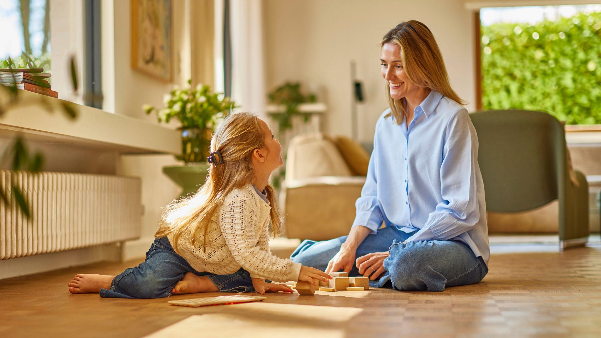 Madre e hija jugando en su piso junto a un radiador por aerotermia