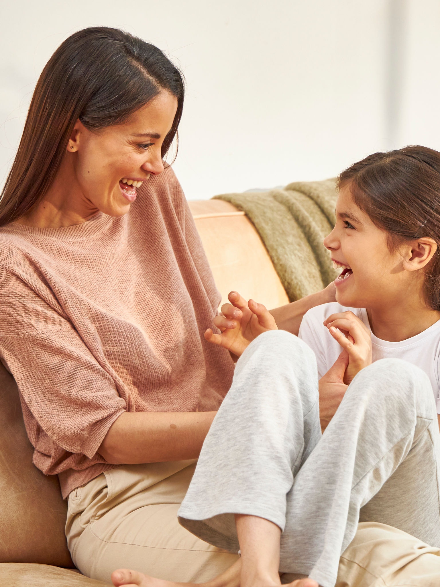 Dos chicas jóvenes sentadas en un sofá al lado de una mujer adulta, sonriendo y disfrutando de un aire saludable.