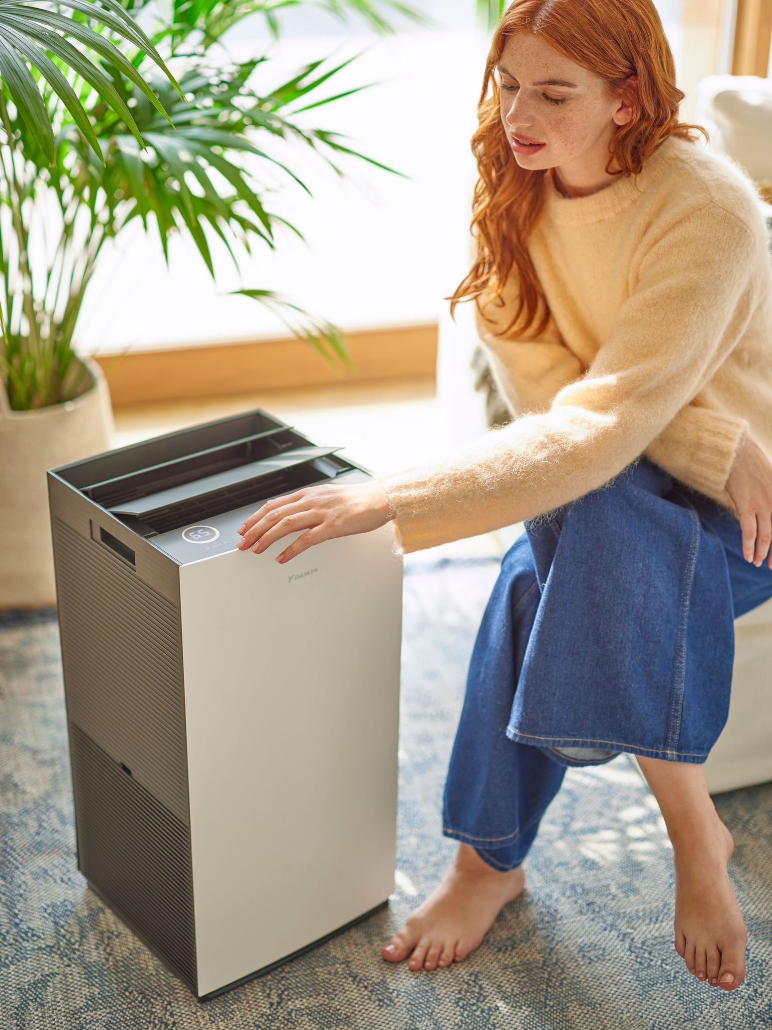 Mujer en la sala de estar ajustando los controles de un purificador de aire Daikin