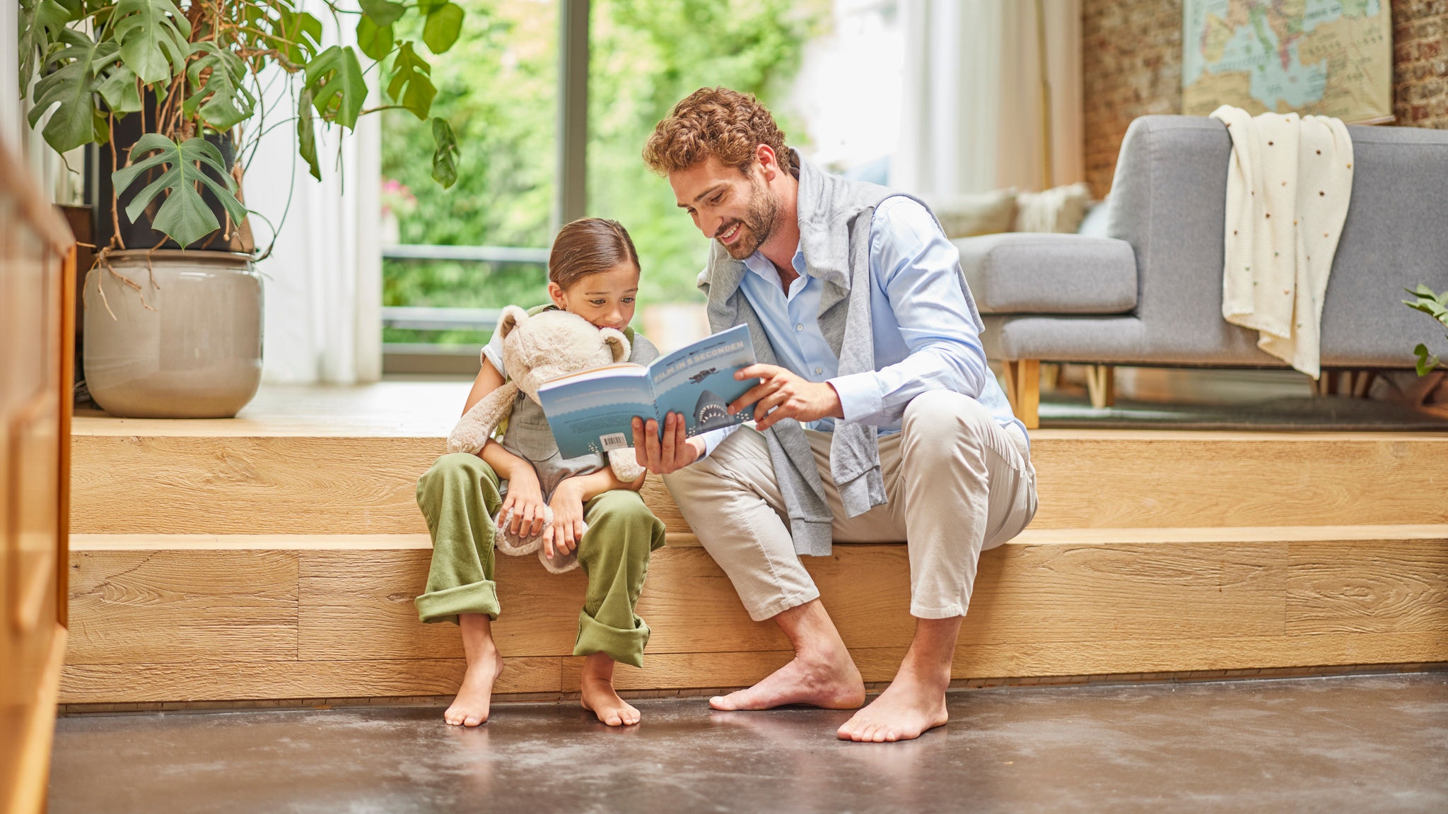 PAdre e hija leen un cuento con sus pies apoyados en el suelo radiante por aerotermia de Daikin