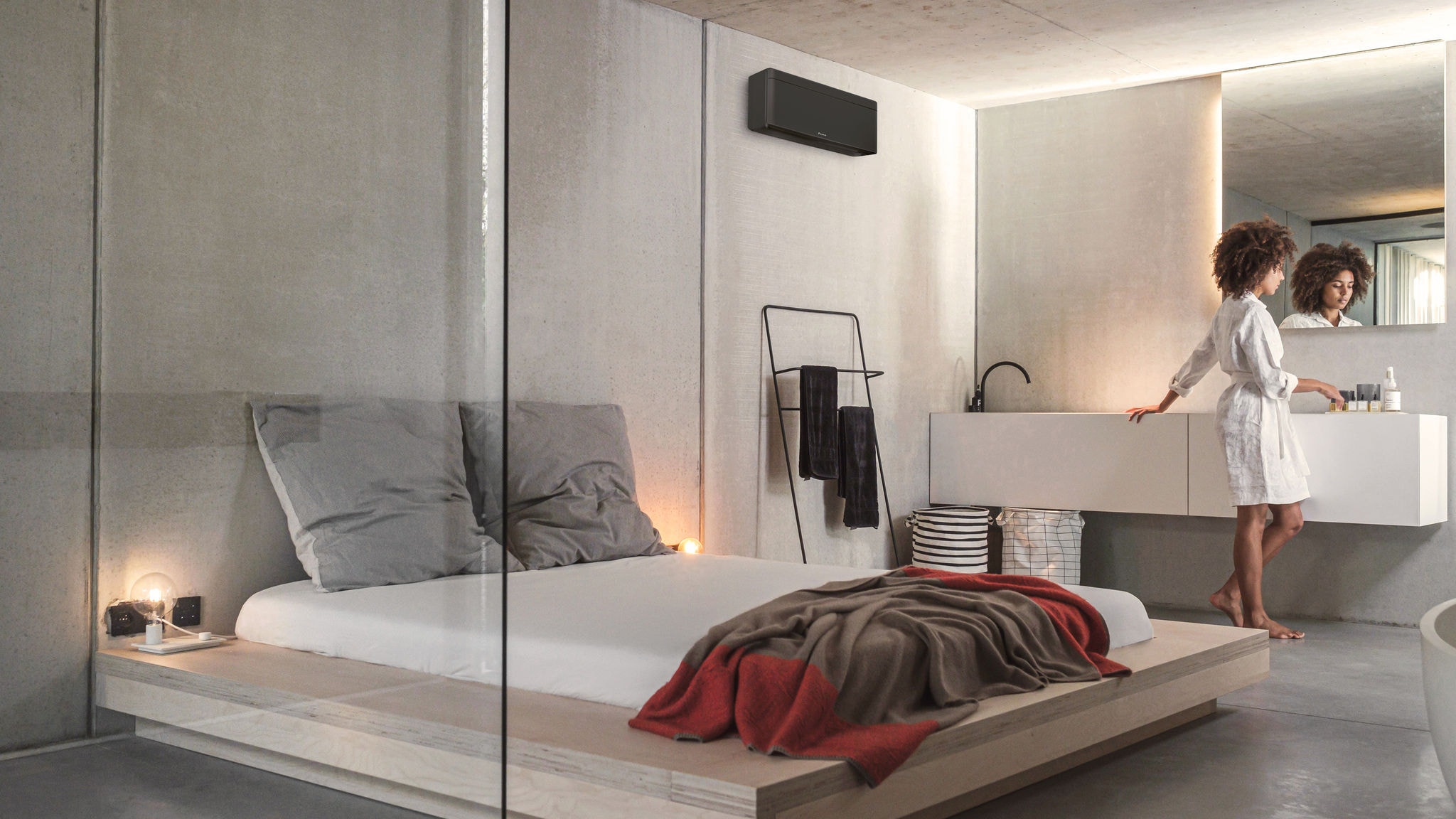 Una mujer preparándose para comenzar el día en un dormitorio con cuarto de baño integrado climatizado mediante una unidad interior Emura