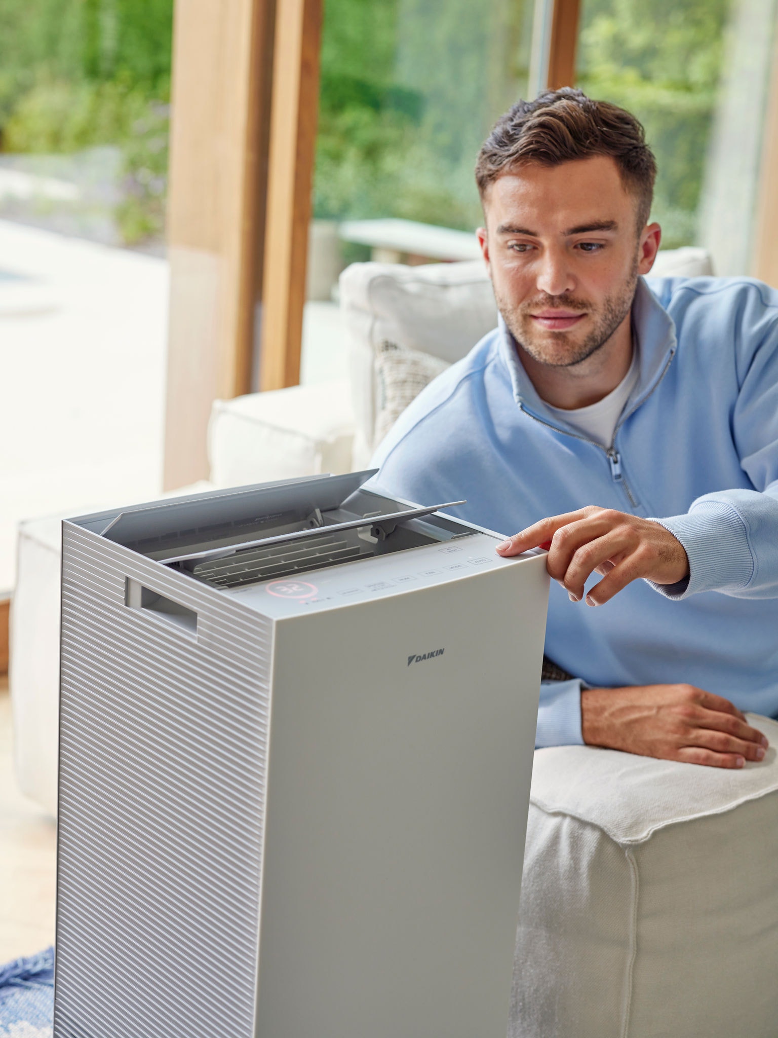 Hombre ajustando el purificador de aire Daikin en la sala de estar para reducir los alérgenos de gato