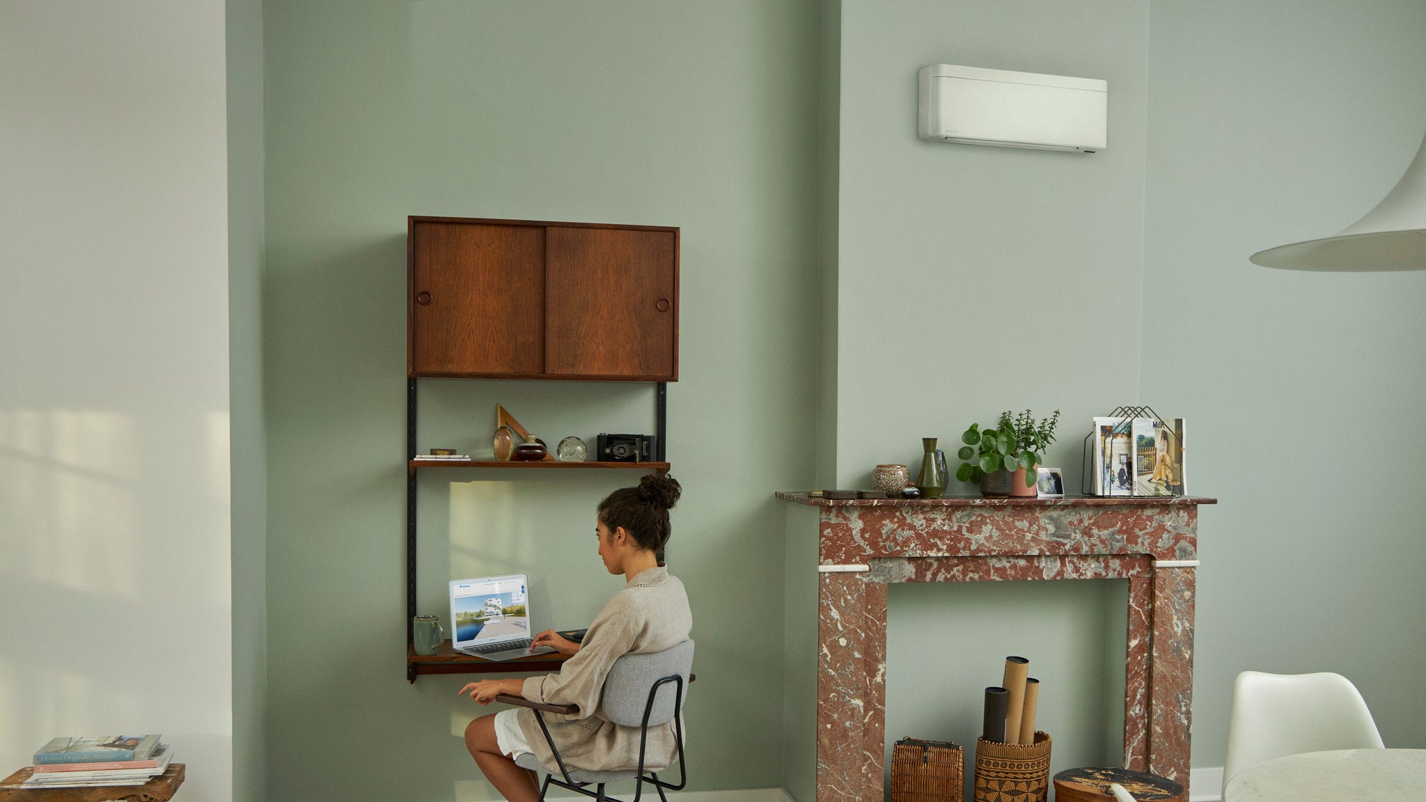 Woman visiting the Daikin Virtual Experience Centre via her laptop at her little desk in beautifully decorated living room