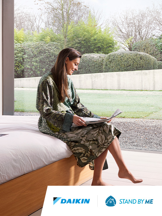 Mujer sujetando un móvil que activa tu tranquilidad con Stand By Me de Daikin, y un montaje de una maleta y un avión