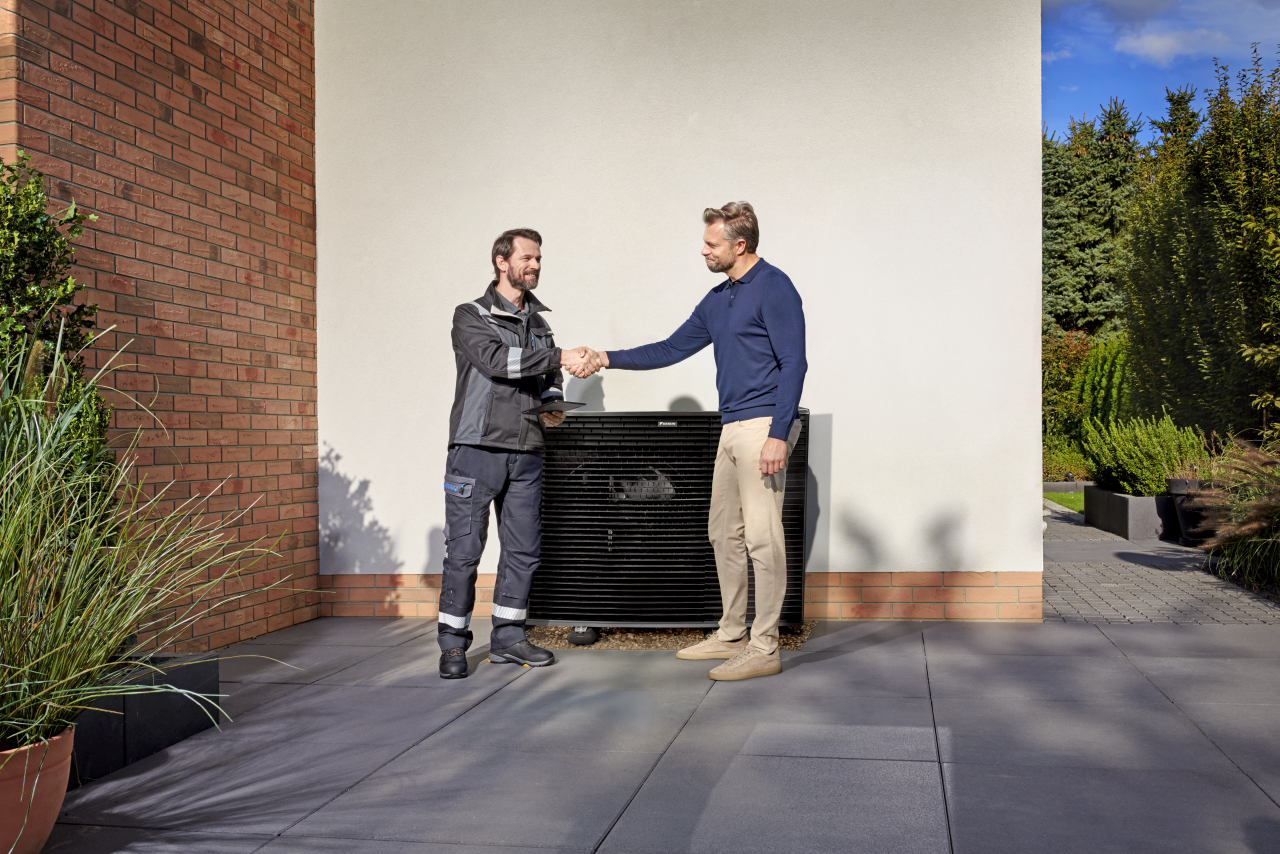 Instalador dando la mano al cliente delante de una unidad exterior Daikin Altherma
